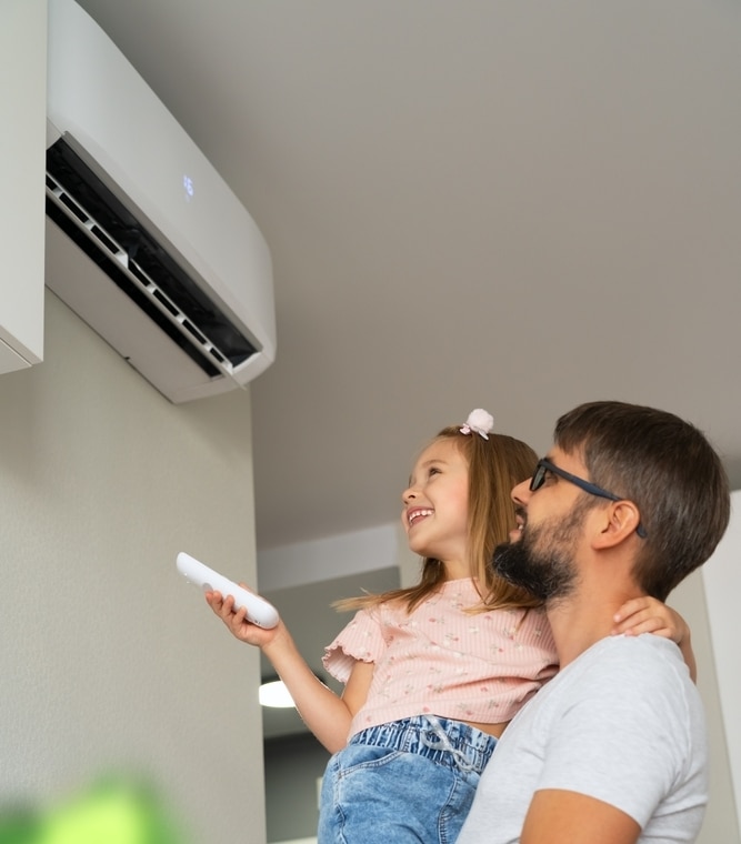 Climatiseur facile à régler : père et fille profitent du frais. Père et fille souriants règlent le climatiseur mural affichant 16 degrés à l'aide d'une télécommande. Moment de complicité.